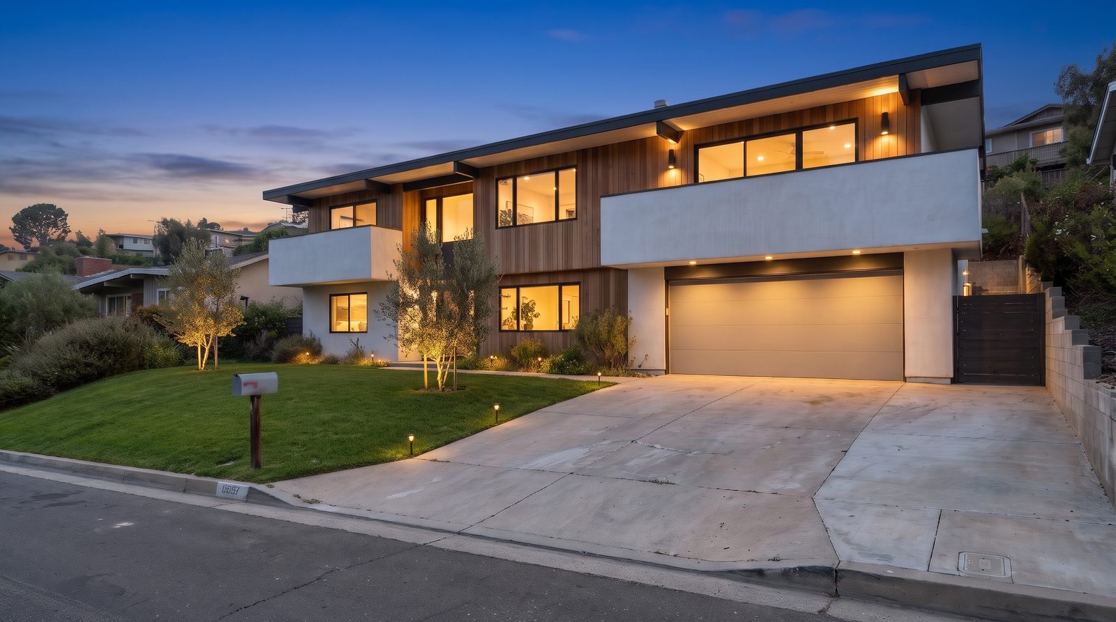 The same house at twilight with a deep blue sky, glowing windows and landscape lights